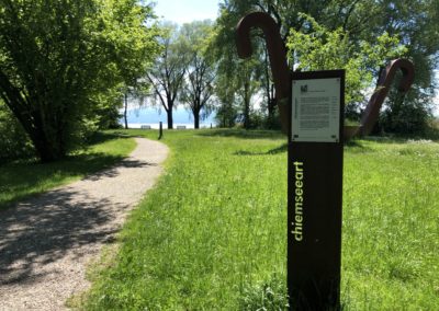 „Chiemseeart“ mit der Skulptur „Aus dem Vollen schöpfen“ an der Römerstraße im Kurpark Seebruck